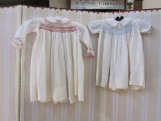 Child's dress with pink  smocking, a child's dress with blue smocking, another and a child's dress