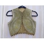 Child's waistcoat, cream ground with gilt coloured applique decoration and bobbles to rim