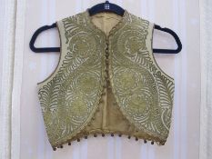 Child's waistcoat, cream ground with gilt coloured applique decoration and bobbles to rim