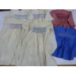 Four cream wool smocked nighties, red check smocked dress and a blue smocked baby's dress