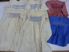 Four cream wool smocked nighties, red check smocked dress and a blue smocked baby's dress