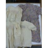 Three cream silk smocked dresses, a rayon floral patterned dress with tie  belt, frill detail to the