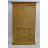 19th century pine linen-press, moulded cornice above two panelled doors enclosing shelves on base of