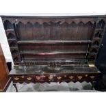 Possibly 18th century oak dresser with moulded cornice above various open shelves and short drawers,