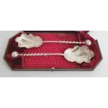 A cased set of silver-coloured metal ornate serving spoons, with ball finials, twist stems, engraved