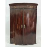 19th century mahogany bowfront wall-hanging corner cupboard, the ogee moulded pediment above two