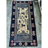 Eastern style rug with cream ground and blue borders, decorated stylised deer, birds and other