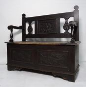 Stained oak bench, carved back above lift up seat, the whole raised on bracket supports and an oak