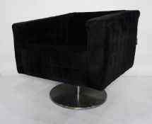 Modern armchair in black upholstery on chrome swivel base