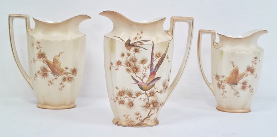 Three Crown Ducal 'Bisque ware' graduating jugs, bird and butterfly design, the largest 21cm high (