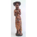 Carved wooden fisherman figure in a black hat, holding catch, 84cm high