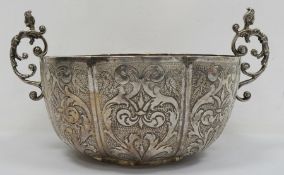 A silver coloured two-handled bowl, hammered and engraved decoration of birds and scrolls, female