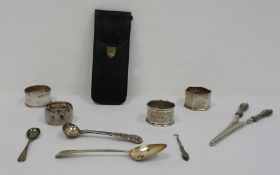 Four assorted silver napkin rings, a silver teaspoon, silver-handled glove stretchers, a silver-