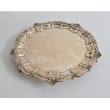 Early 20th century silver salver, circular with scroll and shell decoration, on three claw and
