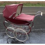 Silver Cross pram with maroon fittings, a tray beneath the pram, double wheels and swan fitting  and