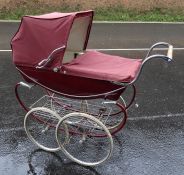 Silver Cross pram with maroon fittings, a tray beneath the pram, double wheels and swan fitting  and