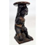 Early 19th century painted and ebonised torchere in the form of kneeling figure, holding aloft a