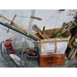 Box of various gardening tools including scythe, shovels and a bow saw, a small quantity of spanners