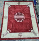 A Chinese wool rug, red ground with central symbol in purple, cream border with symbols and edging