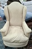 Early 20th century wingback armchair with cream ground upholstery, squat claw and ball front legs