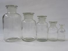 Set of five graduating pharmaceutical clear glass lidded jars and a French pottery oil pourer in the