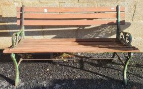 A slatted wood garden bench with metal supports  and a white painted circular metal garden