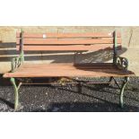 A slatted wood garden bench with metal supports  and a white painted circular metal garden