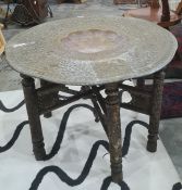Indian table with brass tray top, dished centre, heavily carved folding base