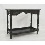 Black painted two-tier table, the rectangular top with carved edge, on turned and block supports