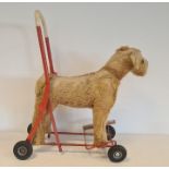 Push-a-long straw-stuffed dog on wheels, 49cm high, worn
