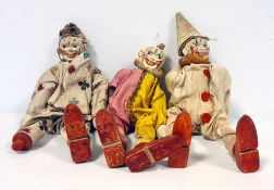 Three early 20th century wooden clown peg dolls with painted faces and in cotton clown costumes,