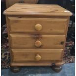 Modern pine bedside chest of three drawers, on bun feet