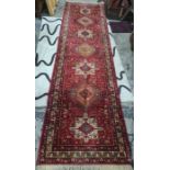 Persian style wool runner, red ground with lozenge and square medallions, floral borders, with one