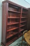 Large stained pine open bookcase, the moulded cornice above assorted shelves, on squat bracket feet,