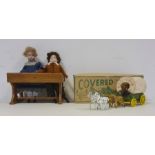 Two porcelain headed dolls in Victorian-style dress, seated at a wooden school desk and 'A Modern