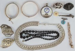 Jet horseshoe brooch, a silver buckle, a gold-coloured bangle, a silver chain necklace, a silver and