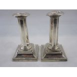 Pair of early 20th century silver-mounted candlesticks with beaded rim, octagonal tapered stem, on a