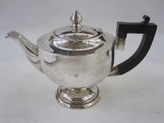 A 1920s silver tea pot, with ebonised handle, pointed finial to lid, plain circular form on a