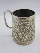Indian white metal mug of tapering cylindrical design, the body decorated with scrolling foliage and