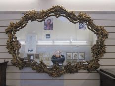 Large gilt ornate mirror, shaped oval with floral foliate, scroll and shell relief borders, 107cm