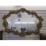 Large gilt ornate mirror, shaped oval with floral foliate, scroll and shell relief borders, 107cm