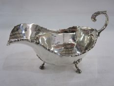 Early 20th century silver cream jug, scroll relief to rim, shaped handle and spade feet, London