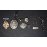 A white metal locket, the obverse with cross, IHS and winged cherub masks, the reverse with bust