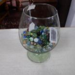 A collection of vintage marbles in a large brandy glass.