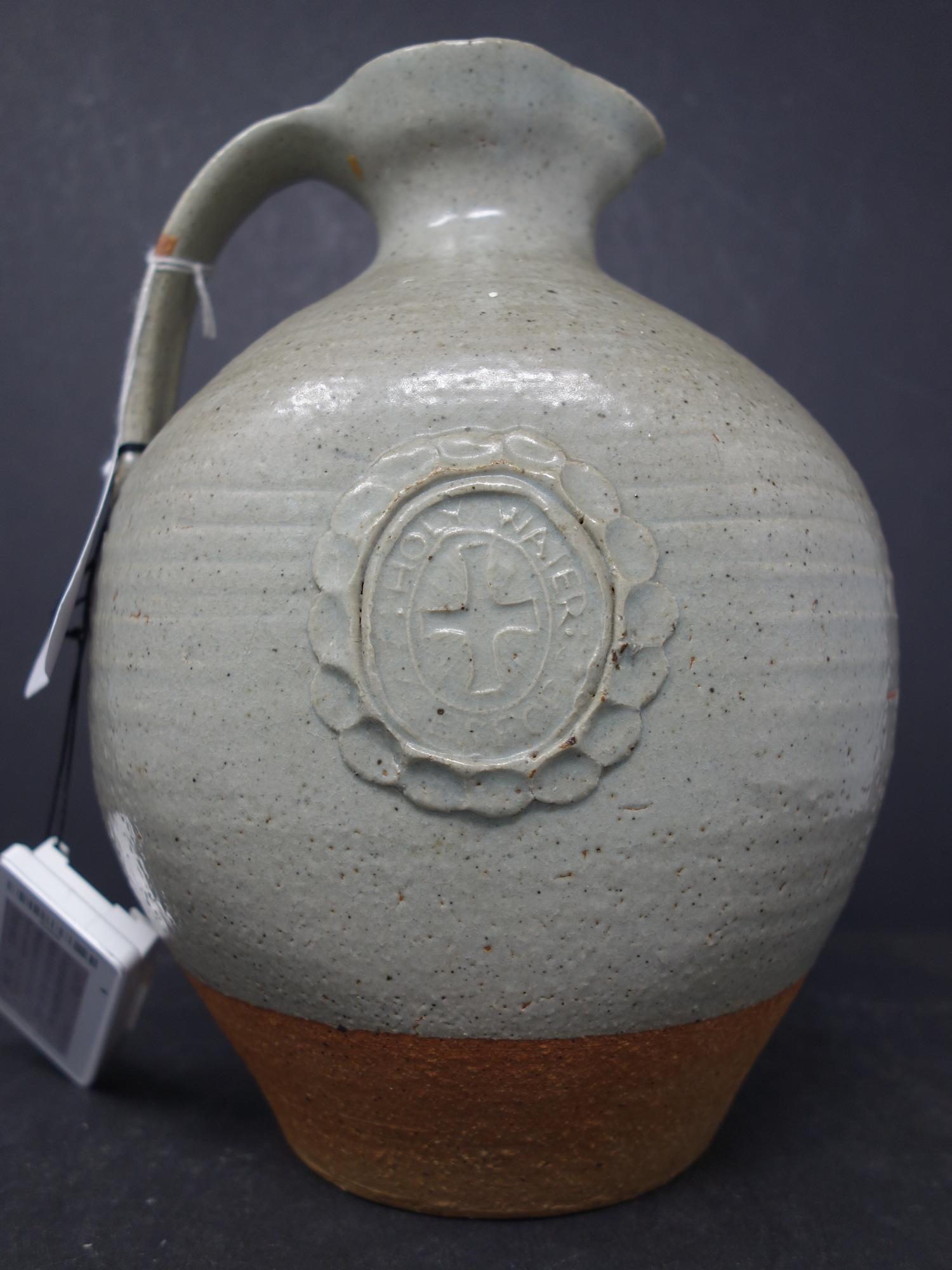 A holy water jug in stoneware with a light green glaze and decorative cartouche of virgin and