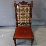 A Victorian nursing chair, carved top rail above turned supports, having tapestry embroidered