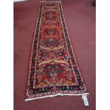 A Northwest Persian Sarouk runner, repeating stylised floral motifs on a rouge field, complimented