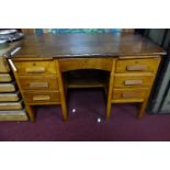 An early 20th century oak desk, having six drawers flanking central short drawer, on square legs,