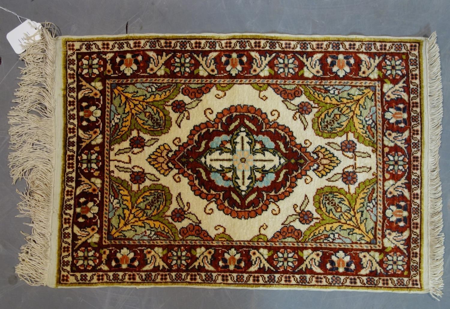 A Persian silk mat with floral medallion, on a beige ground, contained by floral border, 54 x 37cm