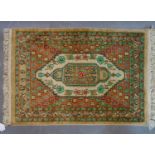 A Persian silk mat with lozenge medallion, on a beige ground, 72 x 49cm
